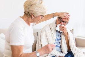 anziano uomo con influenza e in esecuzione naso. moglie assunzione cura di sua marito foto