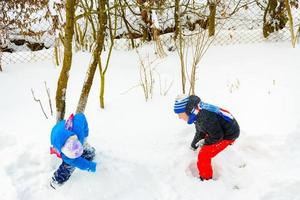 Due ragazzi giocare palle di neve, un' divertimento gioco durante il inverno, un' contento infanzia per bambini. foto