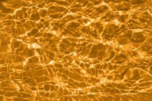 defocus sfocato trasparente oro colorato chiaro calma acqua superficie struttura con spruzzi e bolle. di moda astratto natura sfondo. acqua onde nel luce del sole con copia spazio. giallo acquerello brillare foto