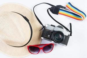 cappello, occhiali da sole e fotocamera vintage isolato su uno sfondo bianco foto