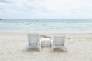 lettini prendisole bianchi sulla spiaggia foto