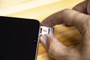 g tecnologia, Internet concetto. sim carta nel smartphone vassoio su di legno tavolo, avvicinamento 6g Rete concetto, alto velocità mobile Internet nuovo età Rete, attività commerciale concetto foto