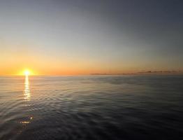 marino. il sole sorge a partire dal il acqua foto