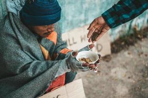 persona dà a un mendicante sul lato della strada foto