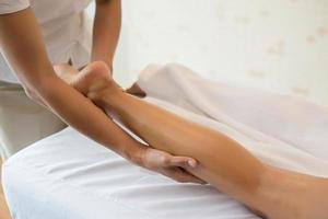 primo piano del massaggiatore che massaggia la gamba femminile al salone della stazione termale foto