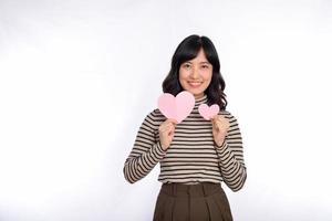 bellissimo giovane asiatico donna Tenere un' carta cuore mentre in piedi contro bianca sfondo. bellissimo giovane asiatico donna con carta cuore. foto
