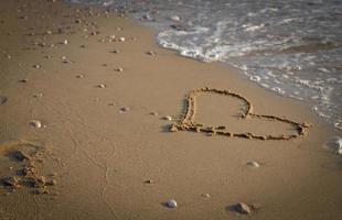 cuore sabbia amore prima il mare. concetto di san San Valentino gratuito foto