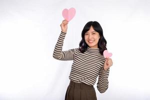 bellissimo giovane asiatico donna Tenere un' carta cuore mentre in piedi contro bianca sfondo. bellissimo giovane asiatico donna con carta cuore. foto