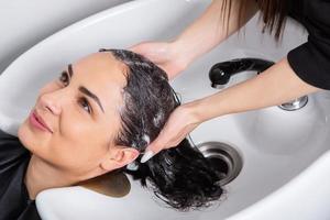 professionale parrucchiere lavaggio capelli di giovane donna nel bellezza salone.. vicino su di donna di capelli nel bellezza salone, acconciatura concetto foto