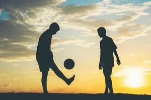 silhouette di bambini che giocano a calcio calcio foto