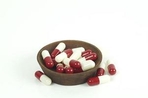 capsule rosse e bianche in tazza di legno isolato su sfondo bianco foto