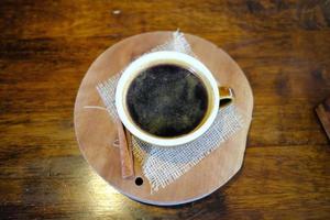 superiore Visualizza di caldo Americano caffè su il di legno tavolo con cannella. foto