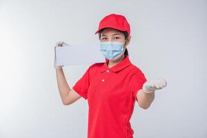 Immagine di un' consapevole giovane consegna uomo nel rosso berretto vuoto maglietta uniforme viso maschera guanti in piedi con vuoto bianca cartone scatola isolato su leggero grigio sfondo studio foto