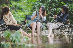 gruppo di donne bevanda birra e inzuppato piedi nel ruscello foto