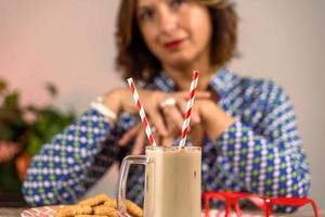 donna vestito nel blu camicia seduta a un' tavolo nel davanti di bicchiere di freddo caffè con Due cannuccia foto