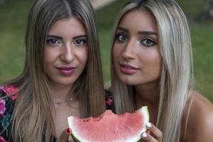 coppia di giovane bellissimo donne mangiare un' fetta di fresco anguria foto