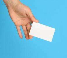 femmina mano Tenere un' bianca nero attività commerciale carta, blu sfondo foto