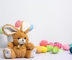 giocattolo coniglietto seduta su un' bianca sfondo e decorativo colorato Pasqua uova foto