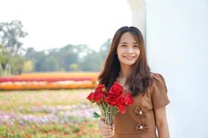 asiatico donna sorridente felicemente tra bellissimo fiori foto
