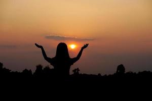 silhouette di umano mano sollevato per rendere un' desiderio, tramonto sfondo foto