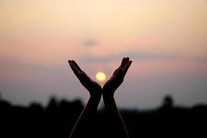 silhouette di umano mano sollevato per rendere un' desiderio, tramonto sfondo foto