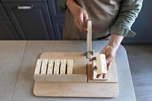 un' donna fa fatto a mano naturale sapone.il finito sapone è tagliare in pezzi utilizzando speciale macchina. casa spa. piccolo attività commerciale foto