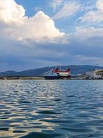 grande nave bianca. traghetto per passeggeri e veicoli. carico di auto e imbarco di persone sulla nave nel porto di volos, in grecia. foto