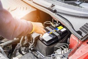 il meccanico di auto usa il voltmetro per controllare il livello di tensione della batteria dell'auto foto