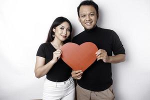 un' giovane asiatico coppia sorridente e Tenere rosso a forma di cuore carta, isolato di bianca sfondo foto