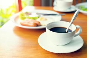 impostato prima colazione con caffè, fritto uova, salsicce foto