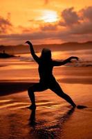 silhouette Immagine di un asiatico donna fare balletto movimenti molto in modo flessibile su il spiaggia foto