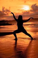 silhouette Immagine di un asiatico donna fare balletto movimenti molto in modo flessibile su il spiaggia foto