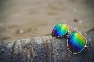 occhiali da sole sulla spiaggia con albero di cocco essiccato foto