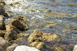 mare costa con pietre nel muschio. onde colpire piccolo rocce. natura sfondo foto