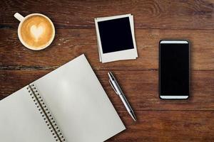 mobile Telefono, taccuino penna, foto telaio e caffè tazza su ufficio di legno tavolo con copia spazio.