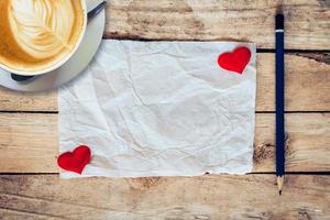 vecchio carta e rosso cuore, caffè tazza con matita su legna sfondo per San Valentino saluto carta. foto