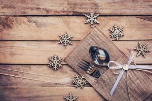 Natale tavolo posto ambientazione e argenteria, i fiocchi di neve su di legno sfondo con spazio. foto