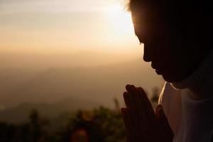 donna che prega le mani con fede nella religione e crede in dio sullo sfondo dell'alba mattutina. gesto delle mani namaste o namaskar, rispetto, posizione di preghiera. foto