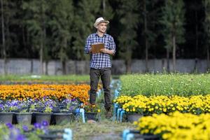 ritratto di asiatico giardiniere Tenere appunti mentre assunzione Nota su irrigazione sistema su rurale campo azienda agricola per medicinale erba e tagliare fiore uso foto