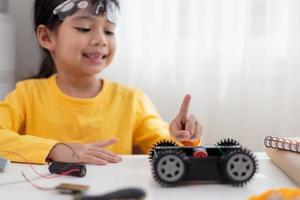 gli studenti asiatici imparano a casa a codificare auto robot e cavi di schede elettroniche in stelo, vapore, matematica ingegneria scienza tecnologia codice informatico in robotica per bambini concetto. foto