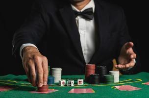 Ritaglia immagine di vicino su uomo commerciante o croupier mescola poker carte scommesse Tenere patatine fritte nel casinò di verde tavolo, commerciante uomo invito scommessa giocando carte. casinò, poker, poker gioco concetto. foto