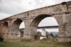 recinzione metallica arrugginita sullo sfondo del vecchio ponte ferroviario, il vecchio viadotto di vorokta, ucraina. carpazi, paesaggio montano selvaggio foto