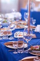 elegante tavolo ambientazione bianca piatti con tovaglioli su blu tovaglia, vasellame servito vuoto tavolo nel un' ristorante, vuoto occhiali, lusso vasellame concetto foto