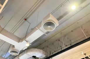 soffitto montato cassetta genere aria condizionatore e moderno lampada leggero su bianca soffitto. condotto aria condizionatore per casa o ufficio foto