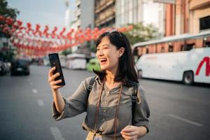 giovane asiatico donna zaino viaggiatore godendo Cina cittadina strada cibo mercato nel bangkok, Tailandia. viaggiatore controllo su lato strade. foto