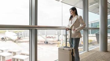 un' giovane donna con valigia , dai un'occhiata nel a internazionale aeroporto , vacanza viaggio e mezzi di trasporto concetto foto