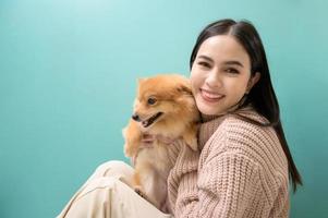 ritratto di giovane bellissimo donna baci e abbracci sua cane al di sopra di verde sfondo. foto