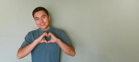 giovane uomo formatura un' cuore con il suo mani con camera per testo foto