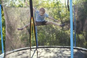 ragazzo salto su trampolino. il bambino giochi su un' trampolino all'aperto foto