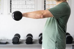 uomo allenarsi nel il interno palestra, uomo sollevamento su un' martello arricciare peso esercizio. bodybuilding manubri nel palestra. formazione nel fitness palestra. foto